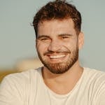 Portrait of a cheerful young man with a beard outdoor, exuding warmth and positivity.